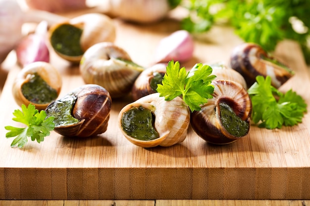 Escargots with parsley on wooden table