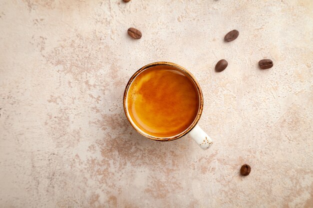 Espresso coffee cup with milk froth on beige vintage pastel background, top view, copy space