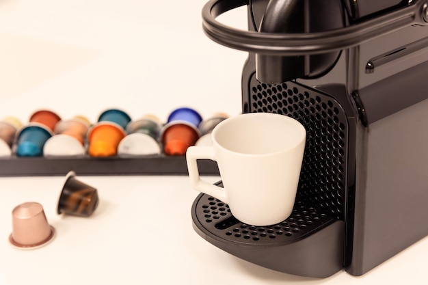 Macchina per caffè espresso con capsule accanto vista ravvicinata con dettagli sfocati sullo sfondo