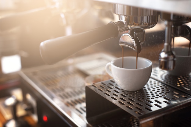 Espresso extraction from coffee machine in coffee shop.