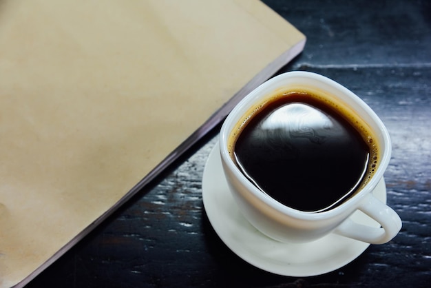 Foto espresso in un bicchiere e notebook su un tavolo di legno nero