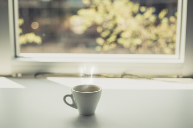 Espresso hot cup of coffee put on table near the window