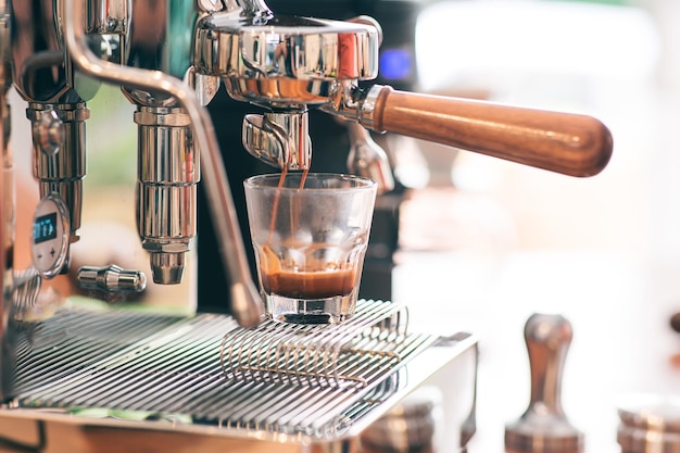 Espresso wordt naar een glas gevuld vanuit een espressomachine met portafilter Detailweergave close-up Inclusief kopieerruimte