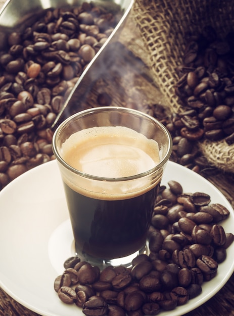 Espressokoffie in glaskop met koffiebonen.