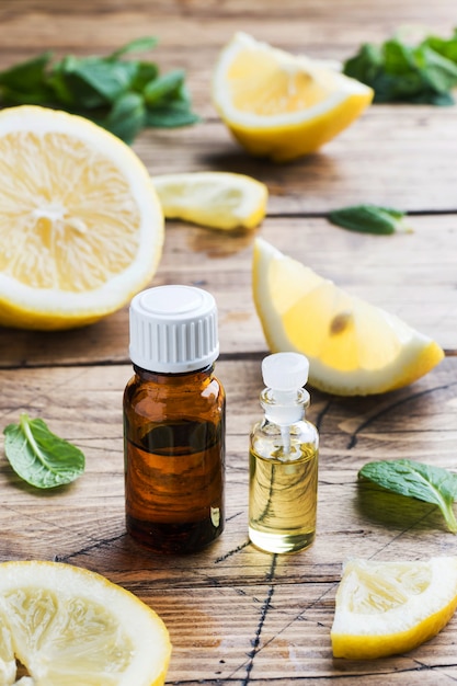 Эфирное лимонное масло в бутылке, кусочки свежих фруктов на деревянный стол. Натуральные ароматизаторы.