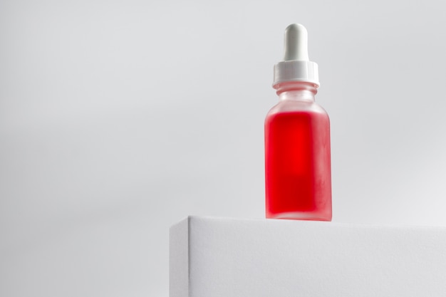 Essential oil bottle on gray block against gray background close up