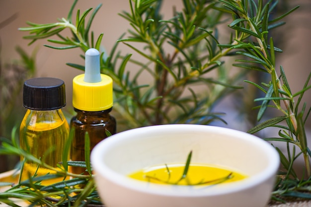 Foto bottiglia di olio essenziale ingredienti spa naturali olio di rosmarino per aromaterapia e pianta di foglie di rosmarino - cosmetici biologici con estratti di erbe