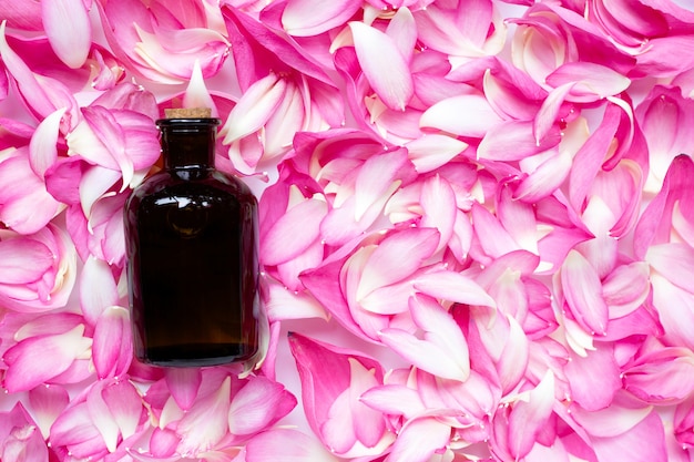 Essential oil bottle on pink lotus petals background.