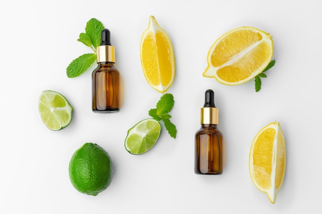 Essential oil bottles and citrus fruit on white background