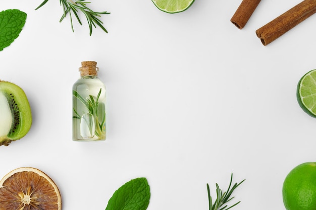 Essential oil bottles and citrus fruit on white background