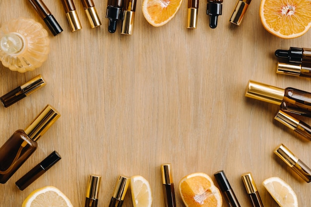 Эфирное масло в бутылках и лимоны апельсины лежат на деревянной поверхности