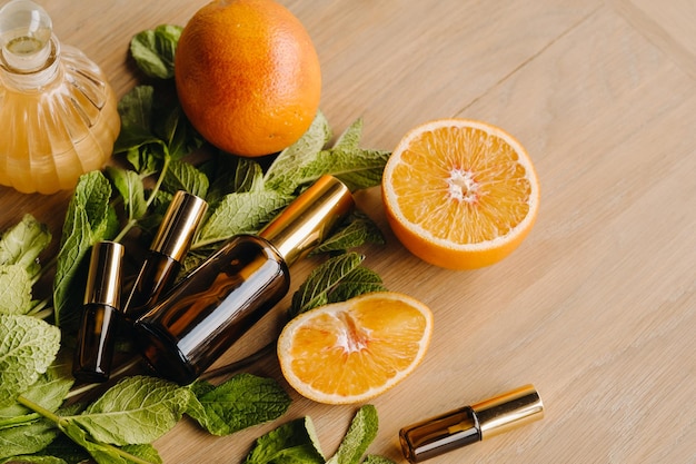 Essential oil in bottles with the aroma of orange and mint lying on a wooden surface