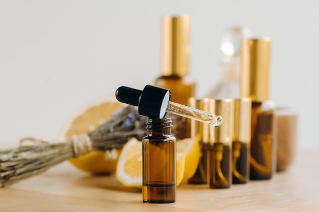 Essential oil in bottles with lemon and lavender fragrance lying on a wooden surface