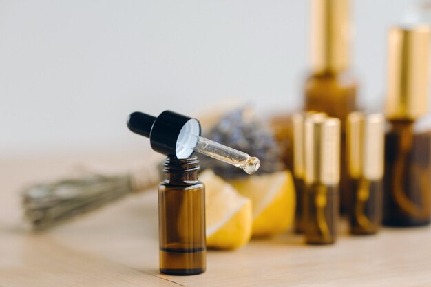 Essential oil in bottles with lemon and lavender fragrance lying on a wooden surface