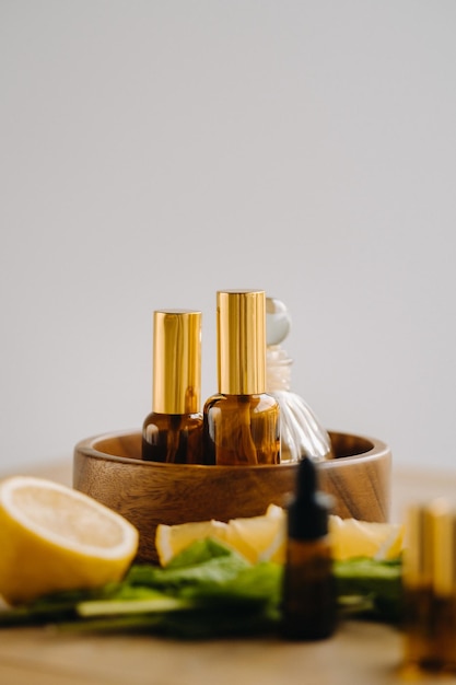 Olio essenziale in bottiglia al profumo di limone e menta adagiato su un piano di legno
