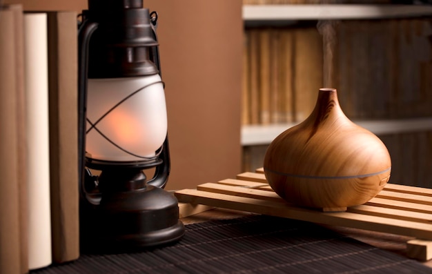 Essential oil freshener on wood with books and lamp on table brown background