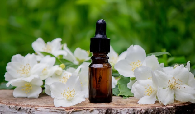 Essential oil and jasmine flowers on a wooden background. Cosmetic procedures. Selective focus