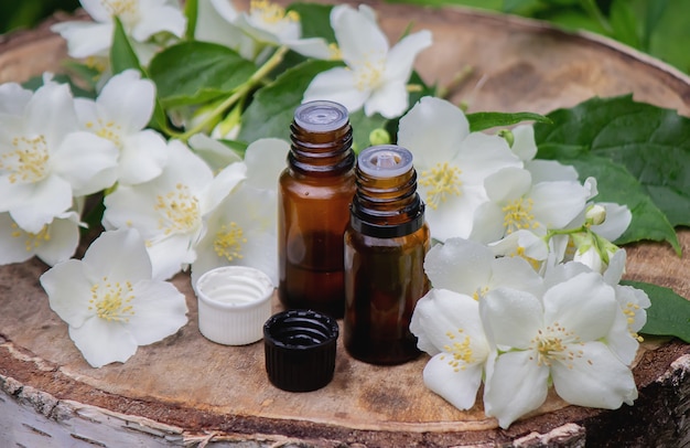 Essential oil and jasmine flowers on a wooden background. Cosmetic procedures. Selective focus