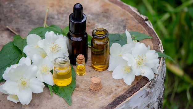 Essential oil and jasmine flowers on a wooden background. Cosmetic procedures. Selective focus