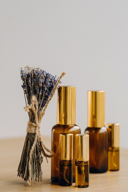 Essential oil in one bottle and dried lavender standing on the surface