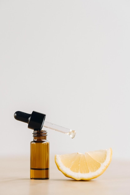 Essential oil in one bottle and lemon lying on the surface