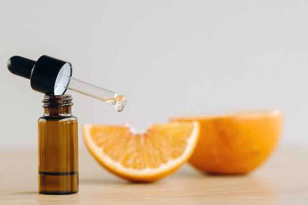 Essential oil in one bottle and orange slices lying on the surface