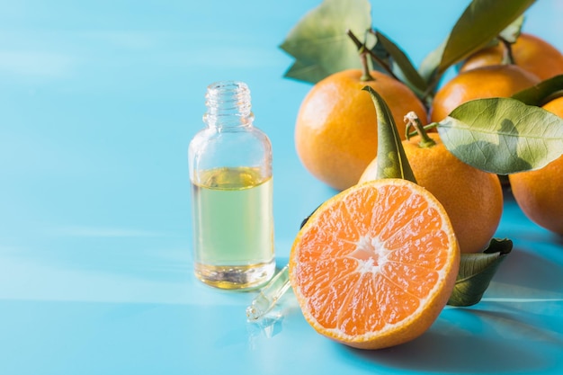 Essential oil of orange mandarin in glass bottle over pastel blue background Skincare concept Space for text