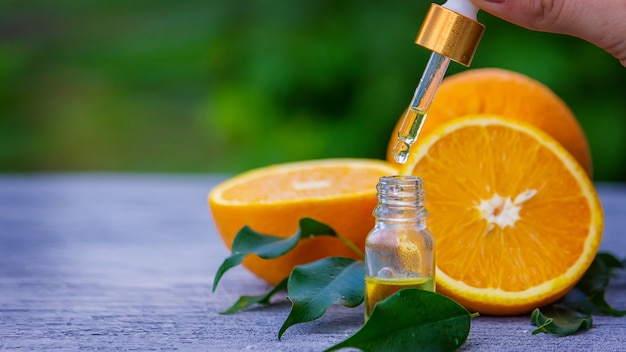 Essential orange oil in a bottle, fresh fruit pieces on the surface