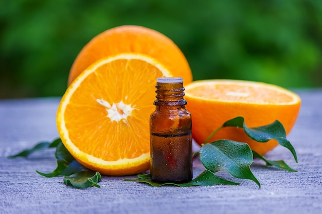 Essential orange oil in a bottle, fresh fruit pieces on the surface