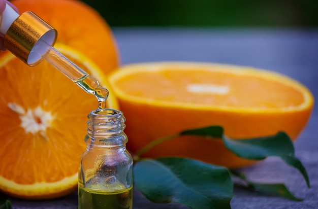 Фото Эфирное апельсиновое масло в бутылке, кусочки свежих фруктов на поверхности