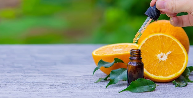 Foto essentiële sinaasappelolie in een fles, stukjes vers fruit op het oppervlak