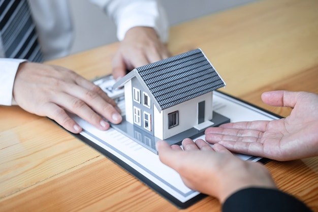 L'agente immobiliare sta presentando un mutuo per la casa e dando casa al cliente dopo aver discusso e firmato il contratto di accordo con il modulo di domanda approvato, l'assicurazione sulla casa e il concetto di investimento immobiliare.