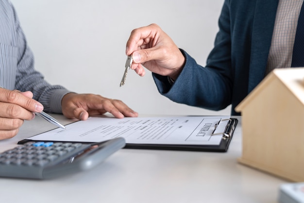 Агент по недвижимости предоставляет жилищный кредит и отправляет ключ клиенту после подписания контракта.