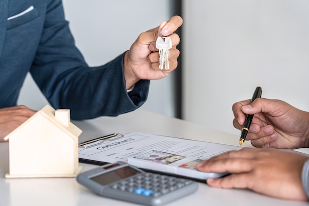 Estate agent are presenting home loan and sending key to customer after signing contract