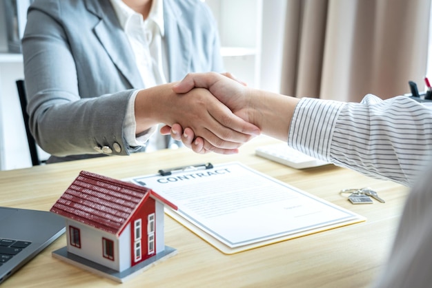 Agente immobiliare e clienti che si stringono la mano per celebrare il contratto finito dopo aver firmato l'assicurazione sulla casa e il prestito di investimento
