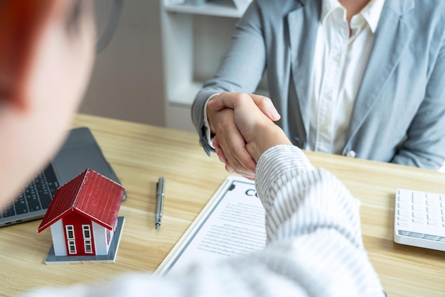 Estate agent and customers shaking hands together celebrating finished contract after signing about home insurance and investment loan