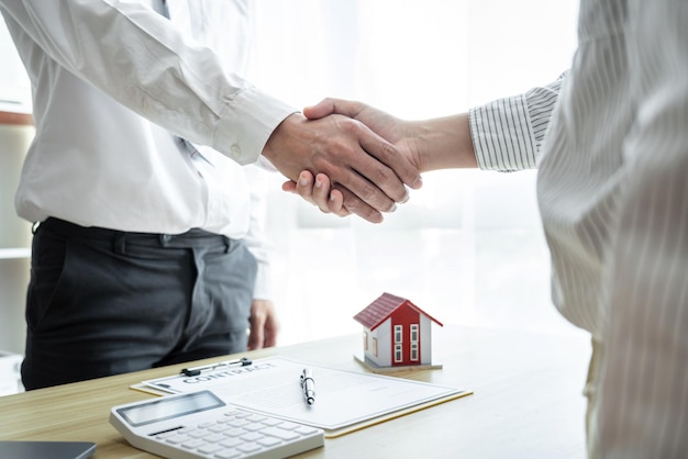 Photo estate agent and customers shaking hands together celebrating finished contract after signing about home insurance and investment loan