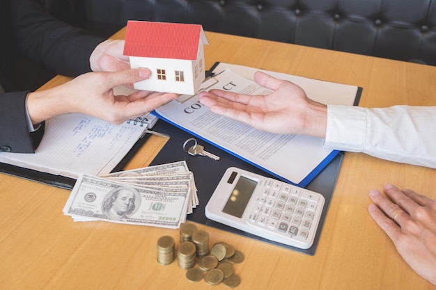 Estate agent giving house keys customer sign agreement property for sale