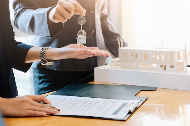 Estate agent giving house keys to man and sign agreement in office