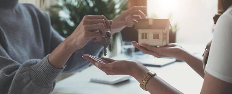 Photo estate agent giving house keys to woman and sign agreement in office
