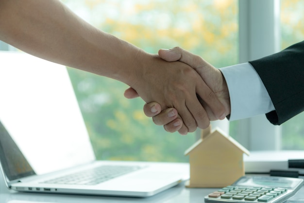 Estate agent in office shaking hands with customers after signing a home purchase contract