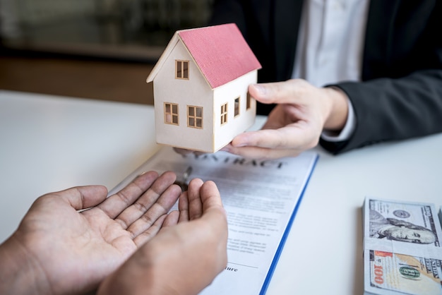 Estate agent presenting home loan and giving house model to customer