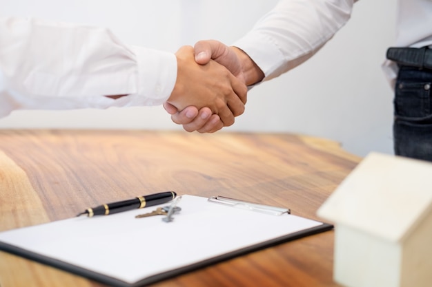 Estate agent shaking hands with customer after contract signature as successful agreement.