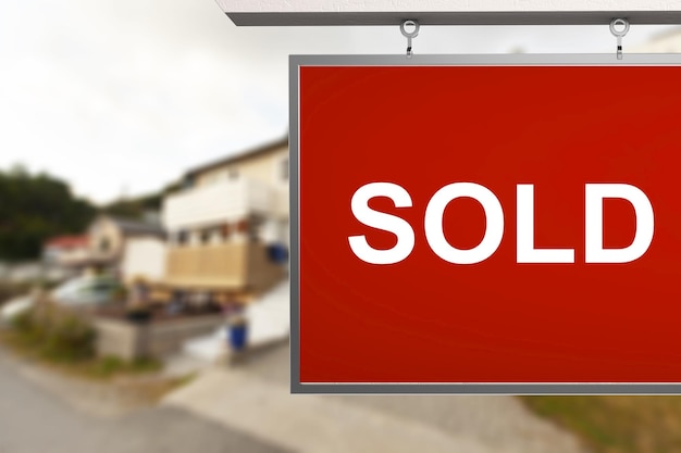 Photo estate agent sold sign with the defocussed street of houses in the background