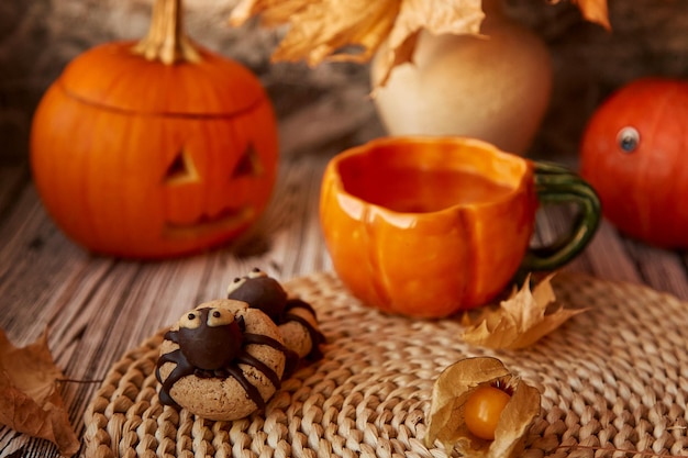 Esthetiek Halloween-spinkoekjes en kopje thee tussen pompoenen en geurige bladeren