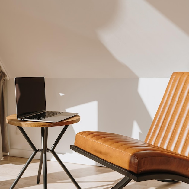 Esthetisch luxe modern thuiskantoor werkruimte interieur met laptopcomputer oranje lederen fauteuil en salontafel Zonlichtschaduwen op de muur Loungeruimte voor ontspanning en chillen