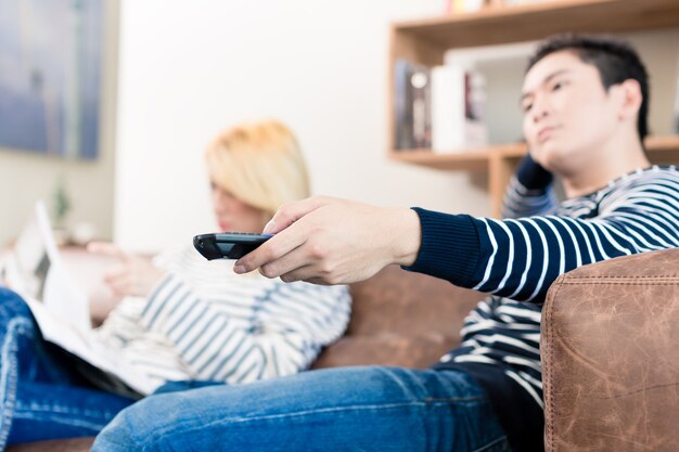 Estranged Asian couple reading and watching tv