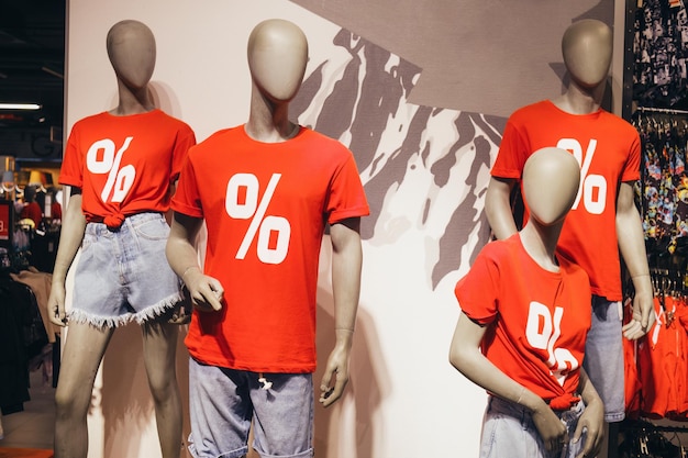 Etalagepoppen in rode t-shirts met een procentteken dat kortingen en verkopen aankondigt Close-up