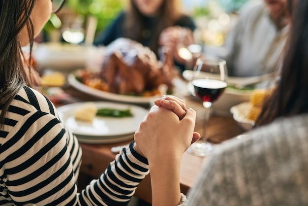 Foto eten bidden en familie hand in hand voor gebed met ouders en kinderen die samenkomen aan een eettafel thuis god aanbidding en dankbare mensen met dankbaarheid genieten van een dankmaaltijd met kalkoen