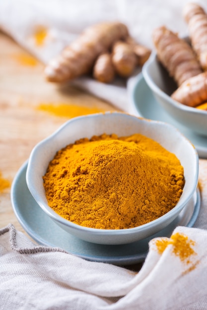 Eten en drinken, dieetvoeding, gezondheidszorgconcept. Rauwe biologische oranje kurkuma wortel en poeder, curcuma longa op een kooktafel. Indiase oosterse kruiden met een laag cholesterolgehalte.